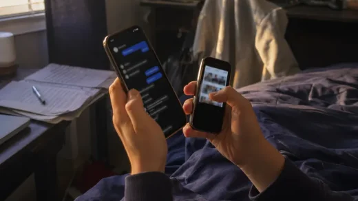 Tonåringshänder håller två mobiltelefoner i sovrumsmiljö